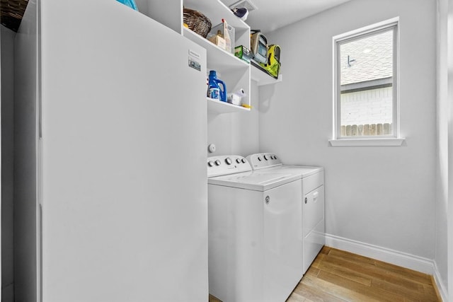 washroom featuring laundry area, light wood-style flooring, independent washer and dryer, and baseboards