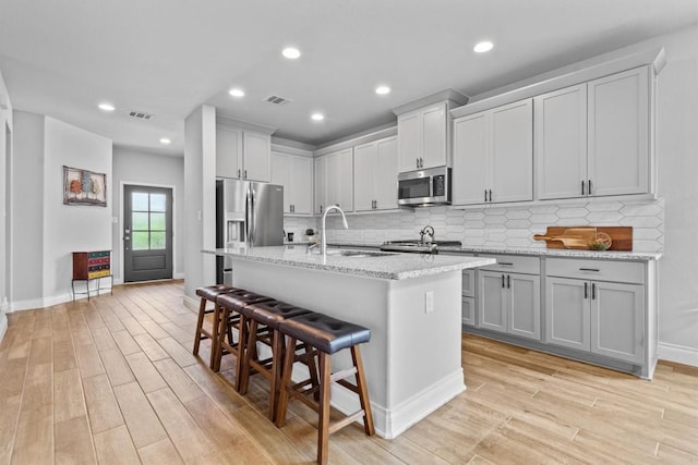 kitchen with light wood-type flooring, a sink, appliances with stainless steel finishes, and visible vents