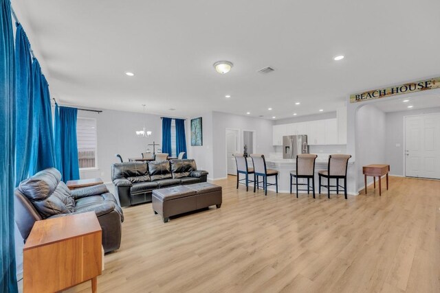 living room featuring a notable chandelier, light wood finished floors, recessed lighting, baseboards, and visible vents
