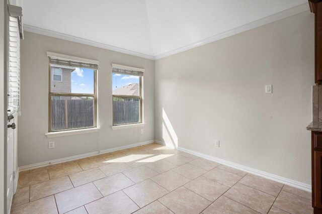 unfurnished room featuring crown molding, baseboards, light tile patterned flooring, and vaulted ceiling