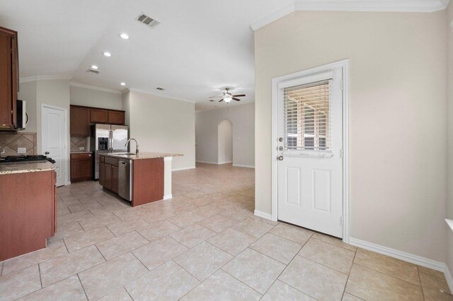 kitchen with appliances with stainless steel finishes, arched walkways, lofted ceiling, backsplash, and visible vents