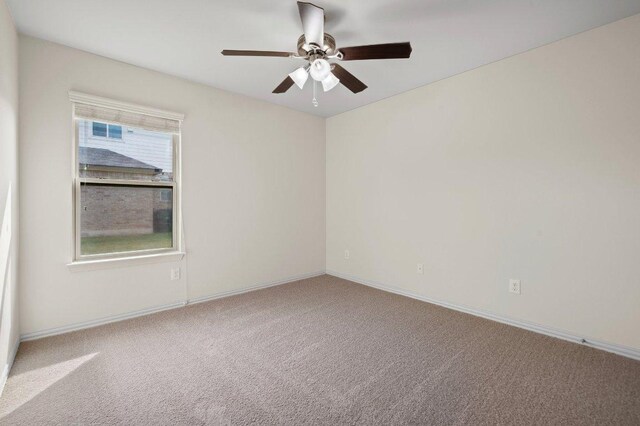 carpeted empty room featuring a ceiling fan and baseboards