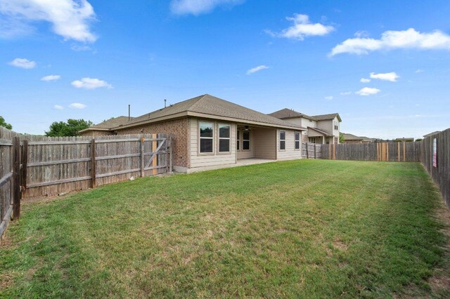 rear view of property featuring a lawn, a fenced backyard, and a patio