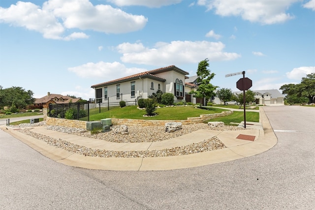 view of front of house with fence, stucco siding, a tile roof, and a front lawn