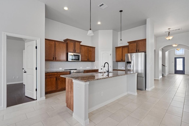 kitchen featuring decorative backsplash, visible vents, arched walkways, a sink, and stainless steel appliances