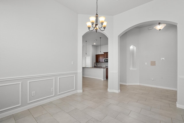 spare room with arched walkways and an inviting chandelier