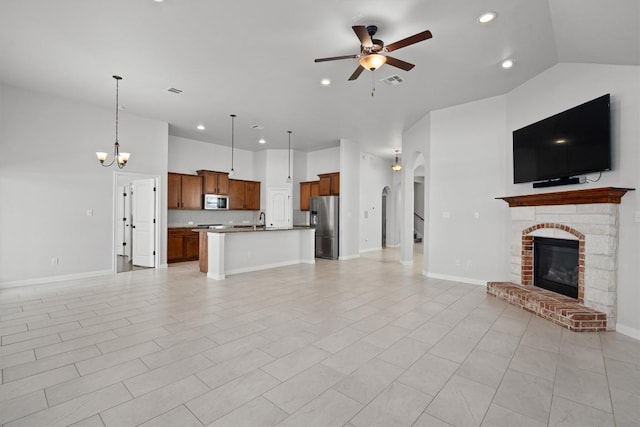 unfurnished living room with visible vents, a glass covered fireplace, recessed lighting, a sink, and ceiling fan with notable chandelier