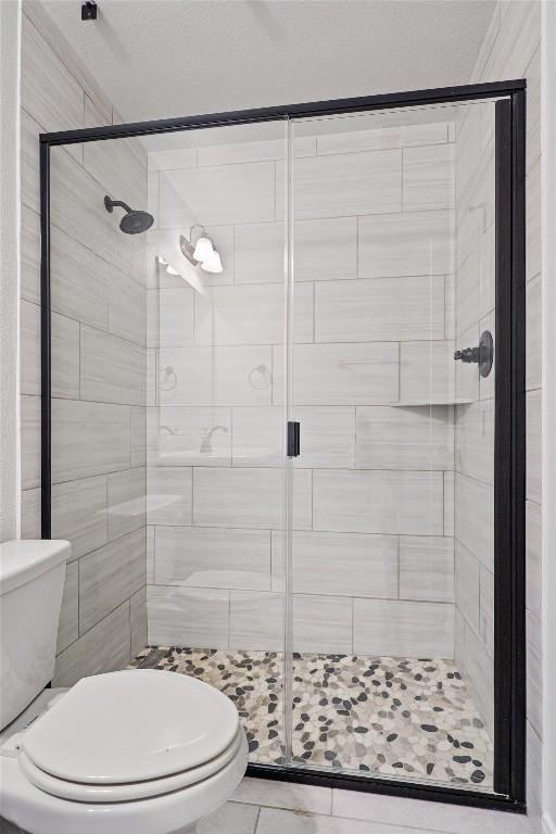 full bathroom with toilet, tile patterned flooring, and a stall shower