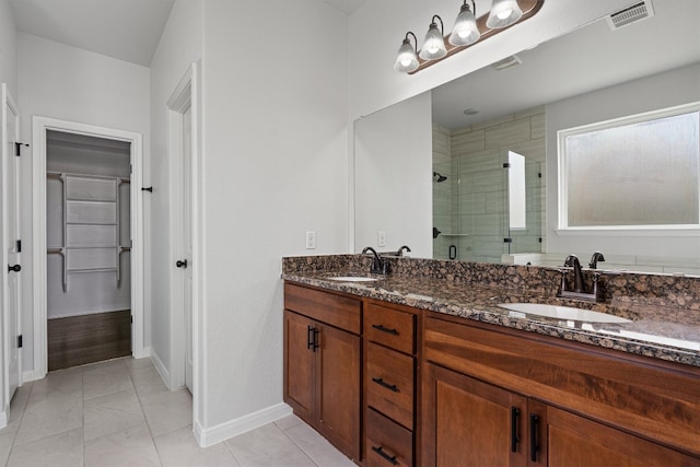bathroom featuring baseboards, visible vents, a shower stall, and a sink