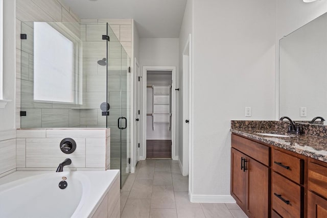 full bath featuring vanity, baseboards, a bath, a spacious closet, and a shower stall