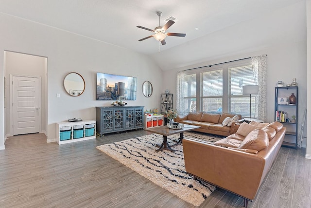 living area with baseboards, a ceiling fan, vaulted ceiling, and light wood finished floors
