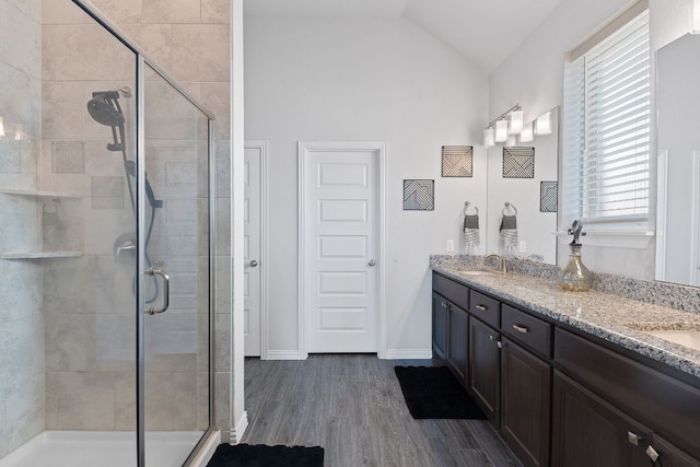 full bath with double vanity, a shower stall, a sink, and a wealth of natural light