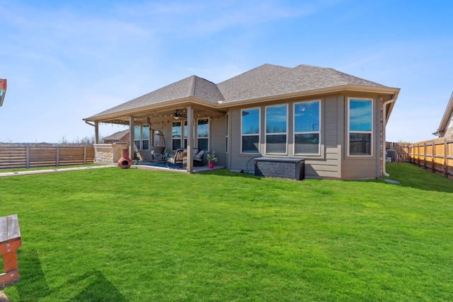 rear view of house with a shingled roof, ceiling fan, a fenced backyard, a patio area, and a lawn