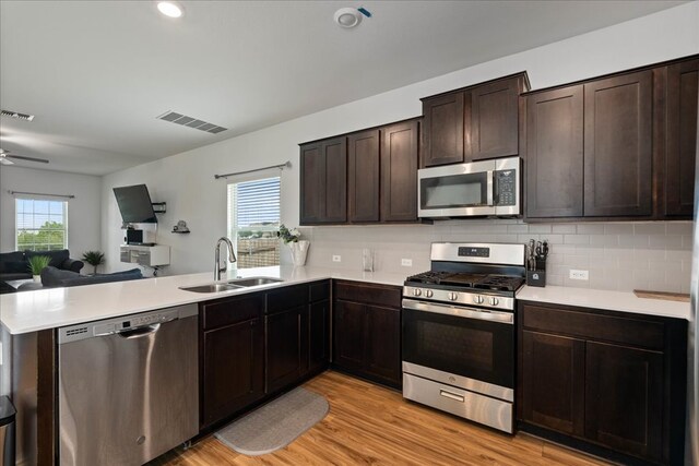 kitchen with visible vents, a sink, a peninsula, open floor plan, and stainless steel appliances