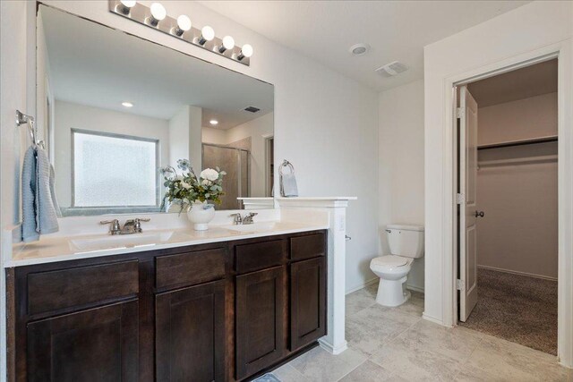 full bath featuring double vanity, toilet, a walk in closet, a shower stall, and a sink