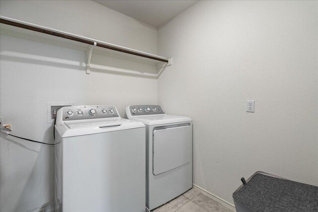 washroom with baseboards, separate washer and dryer, laundry area, and light tile patterned flooring