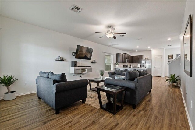 living room featuring baseboards, visible vents, ceiling fan, and dark wood-type flooring