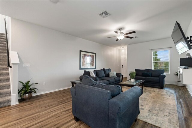 living area featuring ceiling fan, stairs, dark wood-style floors, and visible vents