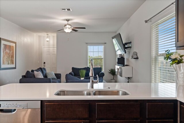 kitchen with dark brown cabinetry, a ceiling fan, dishwasher, a sink, and open floor plan