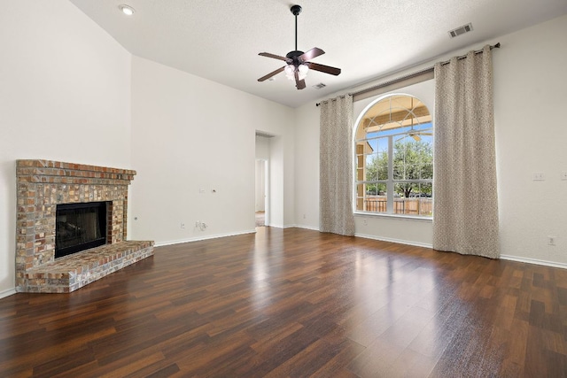 unfurnished living room with ceiling fan, a fireplace, baseboards, wood finished floors, and visible vents