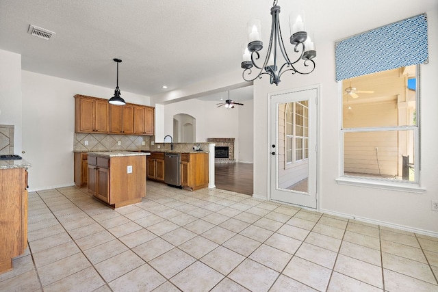 kitchen with visible vents, decorative backsplash, ceiling fan with notable chandelier, and brown cabinets