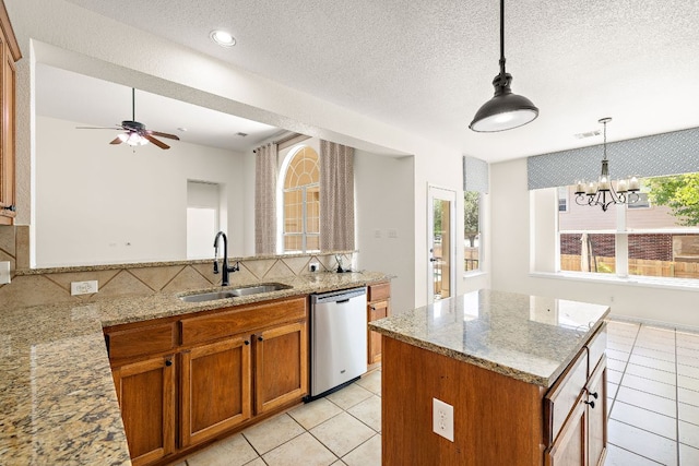 kitchen with brown cabinetry, dishwasher, a sink, light tile patterned floors, and light stone counters