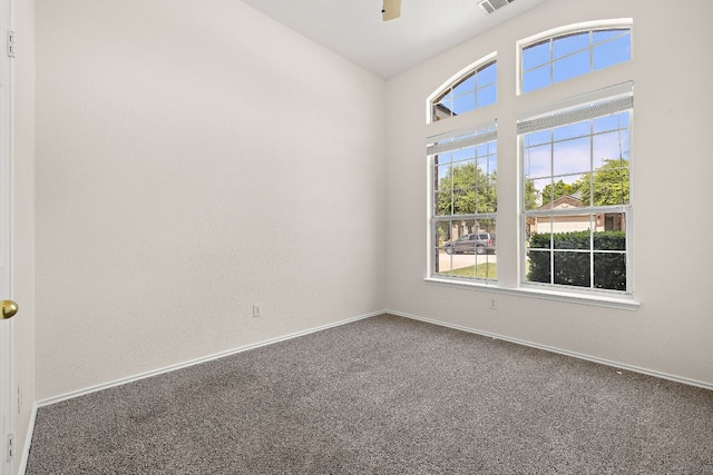 carpeted spare room with baseboards, ceiling fan, and visible vents