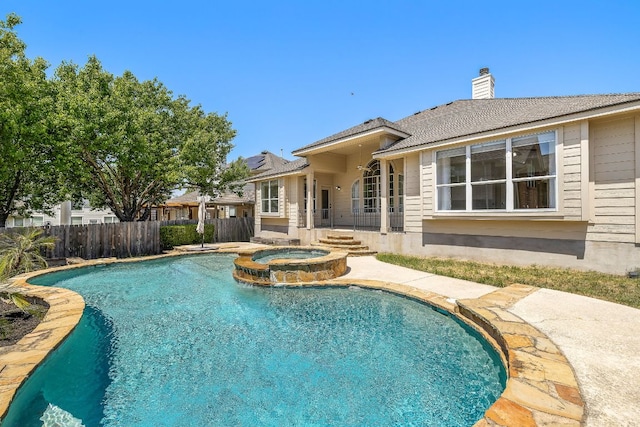 view of pool featuring a patio, fence, and a pool with connected hot tub