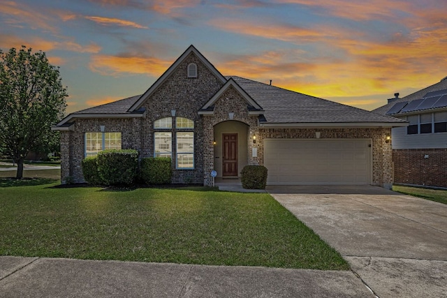 view of front of property with a yard, a shingled roof, and a garage