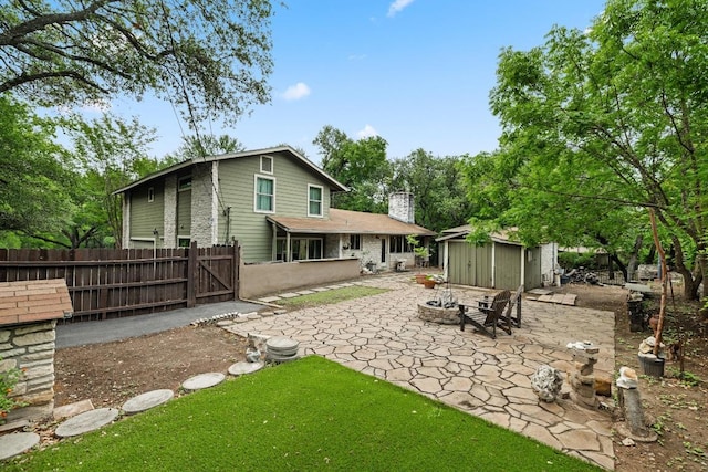 back of property with fence, a storage shed, an outbuilding, a chimney, and a patio area