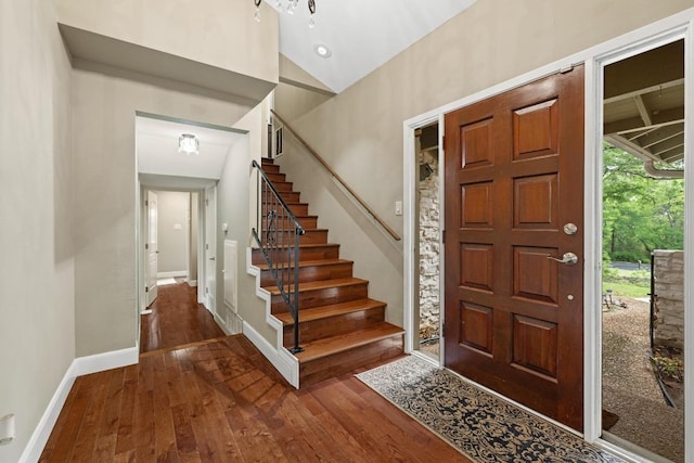 entrance foyer featuring dark wood-type flooring, baseboards, lofted ceiling, and stairway