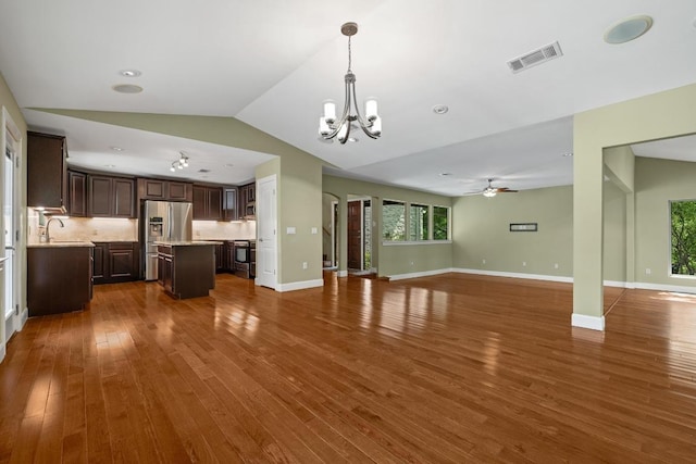 unfurnished living room featuring a sink, dark wood finished floors, ceiling fan with notable chandelier, lofted ceiling, and visible vents