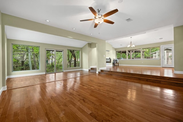 unfurnished living room featuring baseboards, ceiling fan with notable chandelier, hardwood / wood-style flooring, and visible vents