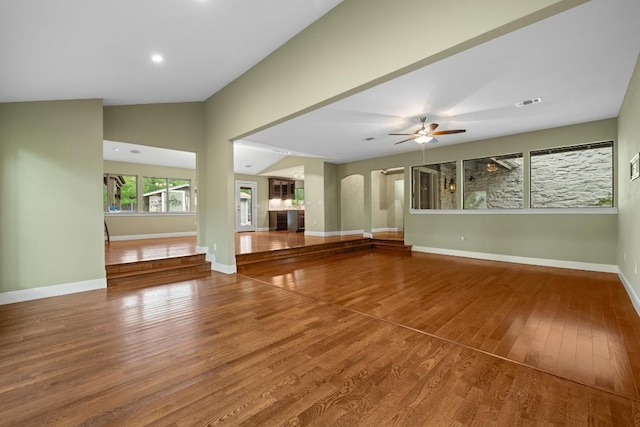 unfurnished living room featuring ceiling fan, visible vents, wood finished floors, baseboards, and lofted ceiling