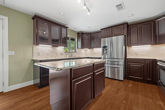 7504 Creekbluff Dr, Austin, TX 78750 - kitchen featuring stainless steel fridge with ice dispenser, dark brown cabinetry, dark wood-style flooring, and glass insert cabinets