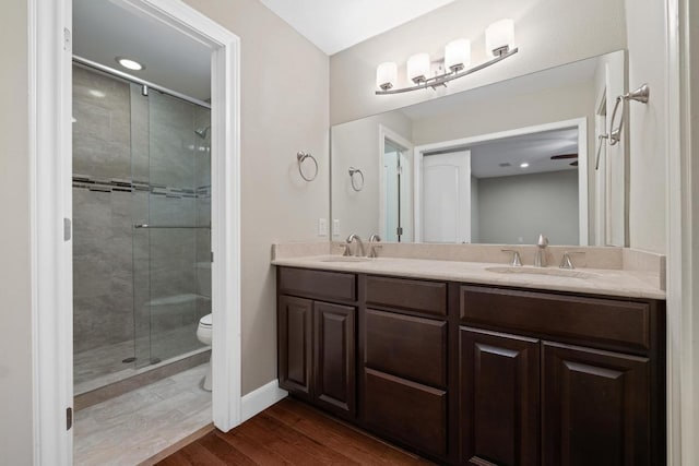 full bathroom featuring a sink, a shower stall, toilet, and wood finished floors