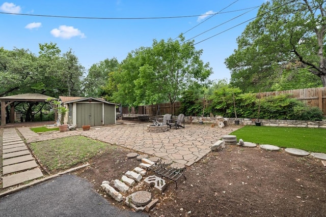 view of yard featuring a gazebo, an outdoor fire pit, a shed, a fenced backyard, and a patio