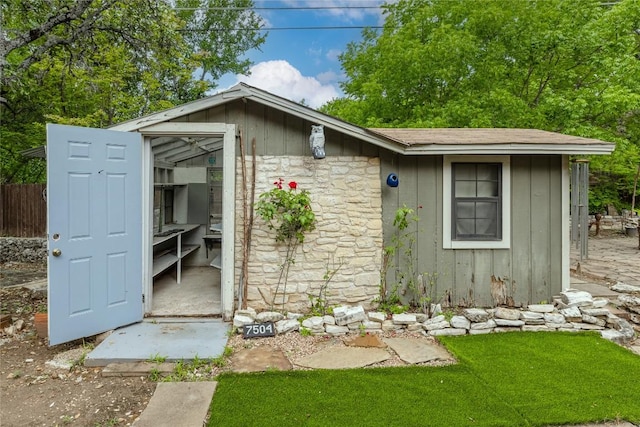 view of outbuilding featuring fence and an outbuilding