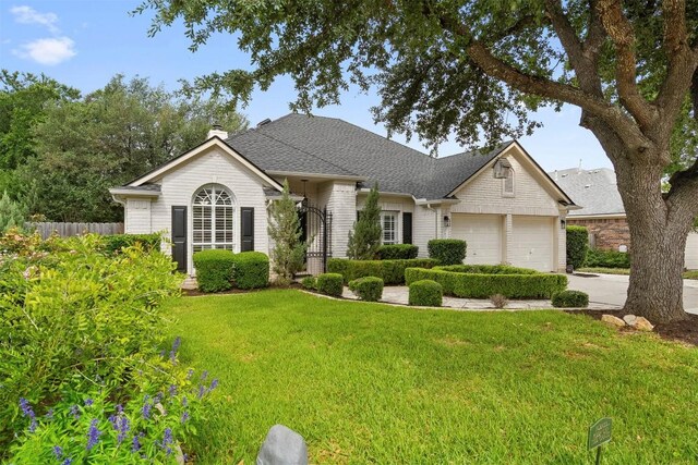 single story home with driveway, a chimney, a front yard, a garage, and fence