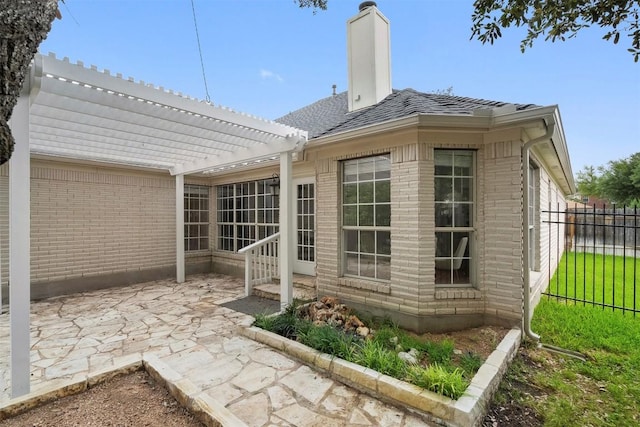 back of property featuring fence, a pergola, brick siding, a chimney, and a patio