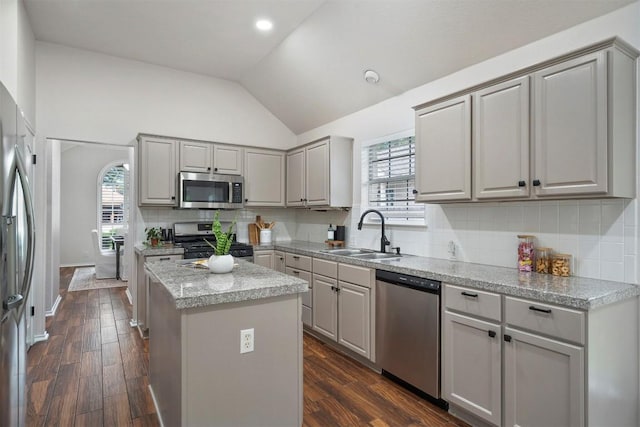 kitchen with appliances with stainless steel finishes, a sink, gray cabinets, a center island, and lofted ceiling