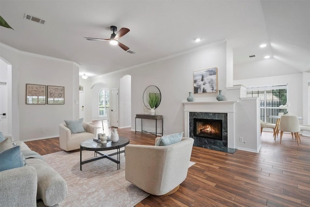 living room with visible vents, a ceiling fan, crown molding, wood finished floors, and arched walkways