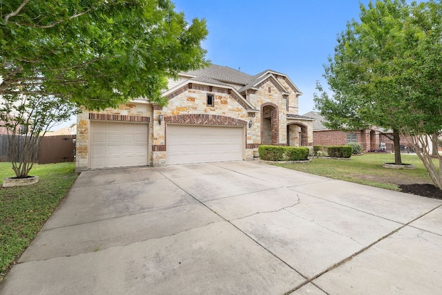 view of front of home featuring driveway, a garage, fence, a front lawn, and stone siding