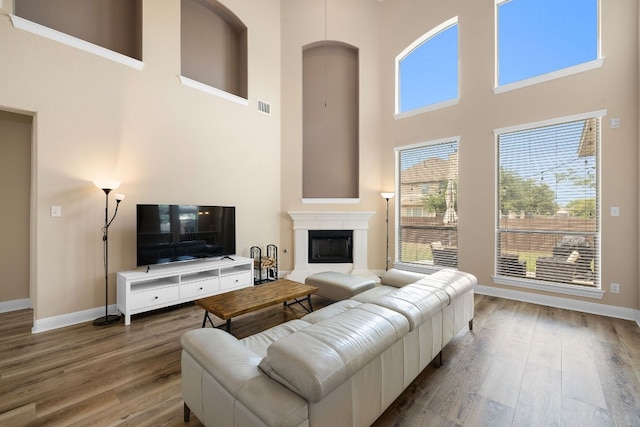 living area featuring baseboards, a high ceiling, visible vents, and wood finished floors