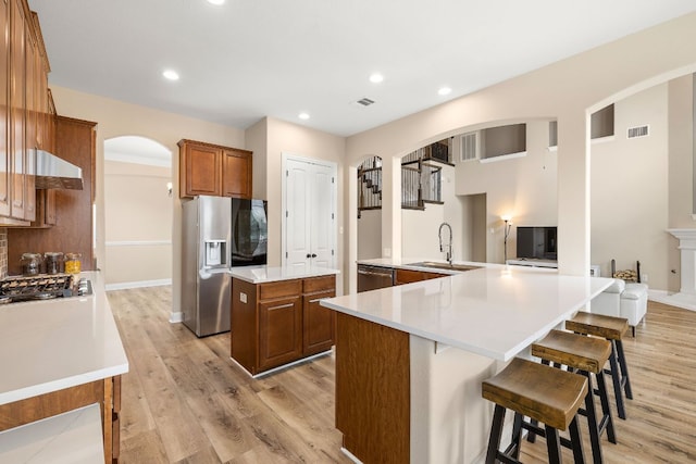 kitchen with visible vents, a sink, a large island, arched walkways, and stainless steel appliances