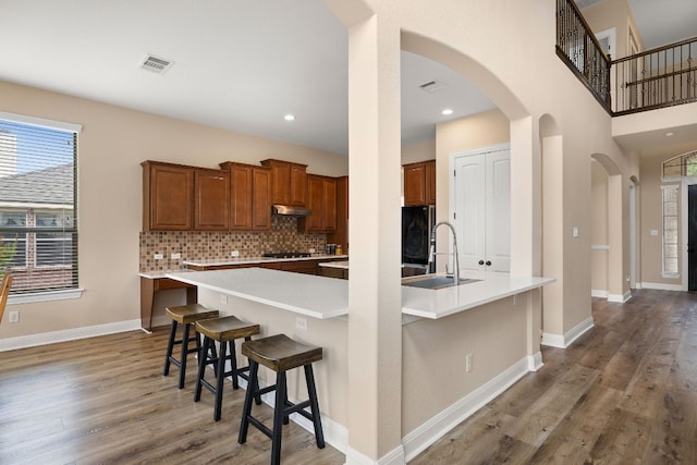kitchen with fridge, a sink, arched walkways, wood finished floors, and visible vents