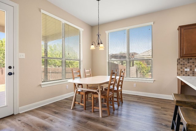 dining area featuring dark wood-type flooring, baseboards, and a notable chandelier