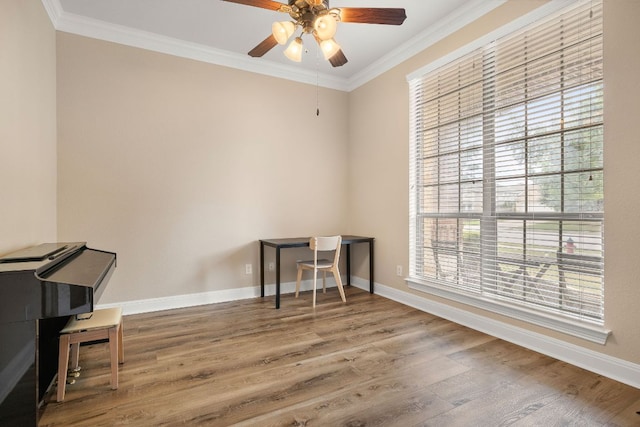 interior space featuring baseboards, ceiling fan, ornamental molding, and wood finished floors