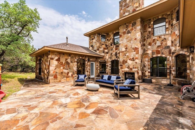 view of patio / terrace featuring fence and an outdoor living space with a fireplace