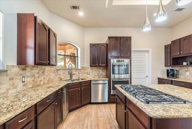 kitchen featuring a sink, backsplash, stainless steel appliances, and visible vents